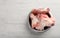 Feeding bowl with raw meaty bones on white wooden table, top view. Space for text