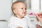 Feeding of cute baby with a spoon in the kitchen