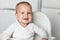 Feeding of cute baby with a spoon in the kitchen