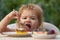 Feeding kids. Child eating cake in the garden outside in summer. Baby eat.