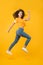 Feel inner energy. Energetic woman running or jumping. Skinny jeans suits her. Sexy girl yellow background. Sensual girl