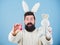 Feeling excited about Easter. Hipster with long rabbit ears holding egg laying hare. Easter bunny delivering colored