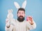 Feeling excited about Easter. Hipster with long rabbit ears holding egg laying hare. Easter bunny delivering colored