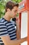 Feeling home sick - Travel. Profile of a handsome young man using a public telephone.