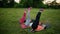 Feeling your abs girls. Group of young athletic people in sportswear doing physical exercises on green grass in summer