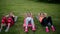 Feeling your abs girls. Group of young athletic people in sportswear doing physical exercises on green grass in summer