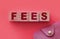 Fees word on Wooden cubes and pink wallet. Small Business startup concept