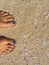 Feet with blue pedicure on the yellow sand beach, woman feet on the sandy beach