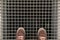 Feet with brown shoes on standing on the on the metal lattice under which is the Elevator shaft