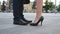 Feet of businessman in black shoes and businesswoman on high-heels standing at city street. Business couple meeting in