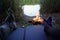 Feet on camping mat in front of bonfire at lake campsite