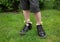 Feet of child boy standing on green grass in black patent leather shoes. Chamomile flower are sticking out of socks