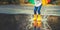 Feet of child in yellow rubber boots jumping over puddle in ra