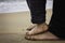 Feet of daddy and boy watching the sea from the beach