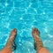 Feet dangling in blue sparkling swimmingpool water