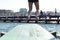 feet of a diver ready to dive off a blue diving board pocking out over the waves in a bay and protected sea bath in Geelong,