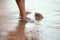 Feet of girl touching water and standing on beach