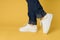 feet jeans fashion shoes white sneakers yellow background