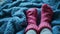 feet in knitted woollen socks peeking out from under a knitted warm blanket in winter. warm and cosy