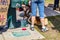 Feet and legs of protesters against guns standing with a corgi dog drinking from a doggie fountain with part of a protest sign sho