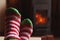 Feet legs in winter clothes wool socks at fireplace background. Woman sitting at home on winter or autumn evening relaxing and