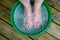 Feet in little plastic tub on wooden decking