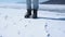 The feet of a man in trekking boots jump and trample in the snow. Close-up.