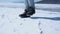 The feet of a man in trekking boots jump and trample in the snow. Close-up.