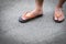 Feet of a man wearing sandals on concrete floor.