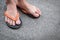 Feet of a man wearing sandals on concrete floor.