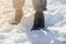 The feet of a man in winter warm shoes on the snow in a frosty winter