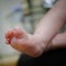 Feet of newborn baby in the hand of mother