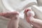 Feet of a newborn baby on white silk background and a white feather. Little baby legs