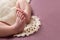 Feet of a newborn girl, folded prayer, on a lace vintage napkin, on a pink background