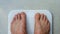 Feet of an obese man standing barefoot on a bathroom scale