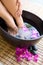 Feet in oriental foot bath with flowers