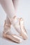 Feet with pink satin pointe shoes by a classical dancer posing