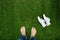 Feet resting on green grass with lying sneakers