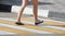 Feet of a running girl at a pedestrian crossing in the city