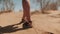 Feet in shoes walking on the sand in the desert, close-up. Woman walking on hot sand. Travel, Adventure.