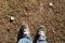 Feet in sneakers on the ground pine needles