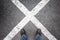 Feet standing on dark urban asphalt with crossing lines