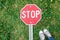 Feet and stop sign on the green grass background. Prohibition concept