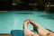 Feet of a sunbathing woman at sunbed next to a swimming pool