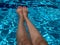 Feet swimming pool water with coconut tree shadow. Selfie of legs and barefoot with red pedicure and manicure nails on blue sea