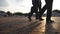 Feet of three businessmen walking in city with sun flare at background. Business men commute to work together. Confident