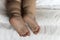 feet of toddler baby girl wearing diapers lying on white bed at home. plump legs of sleeping one year old caucasian