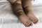 feet of toddler baby girl wearing diapers lying on white bed at home. plump legs of sleeping one year old caucasian