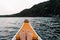 feet together resting on the prow of a white and orange wooden canoe heading into the forest navigating the lake waters