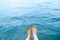 Feet top view in the aqua blue water background abstract. Beautiful adult woman body legs and barefoot on summer beach scene.